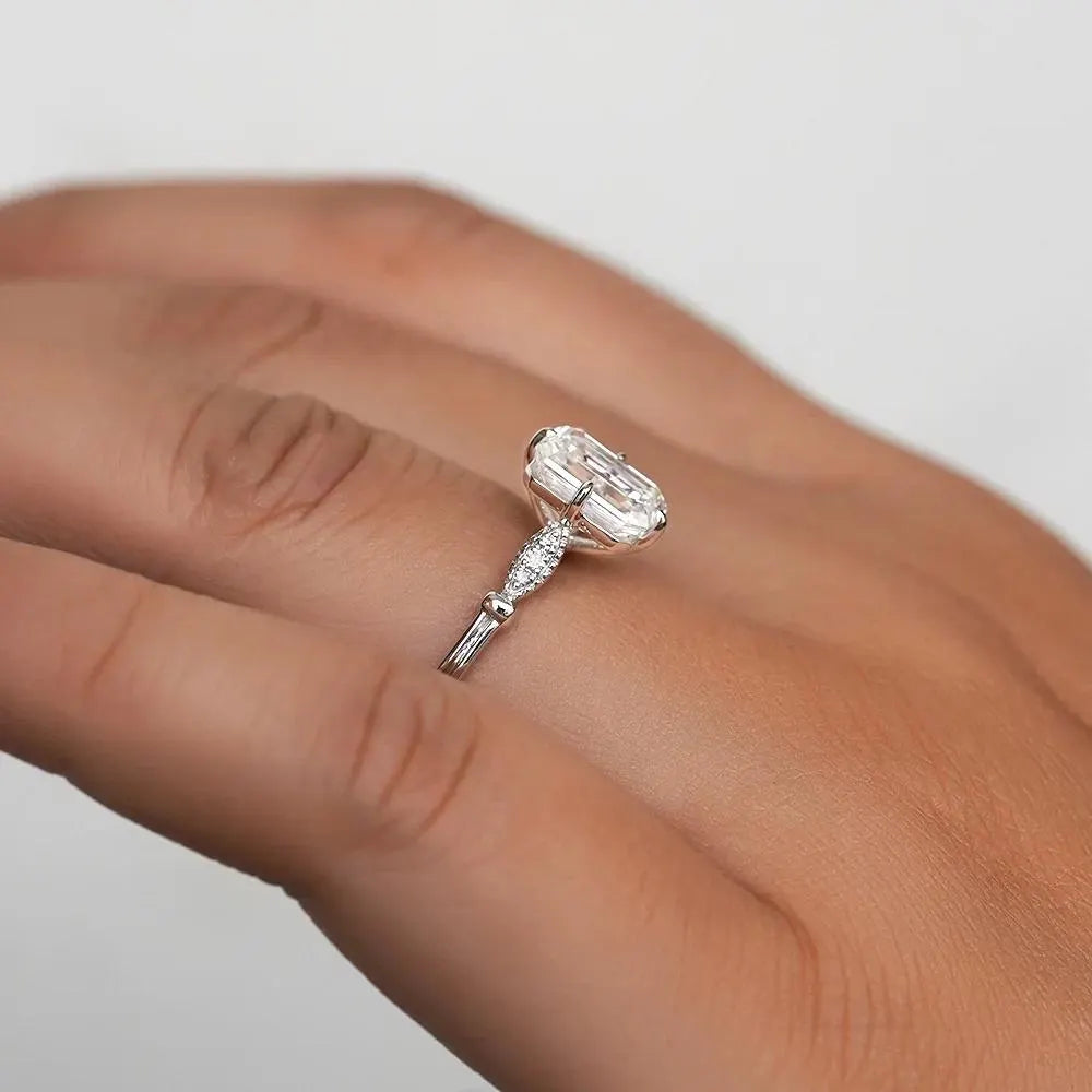Elegant Emerald Cut Solitaire Engagement Ring In White Gold With Dainty Accent Stones. A Timeless Moissanite Wedding Or Promise Ring For Her