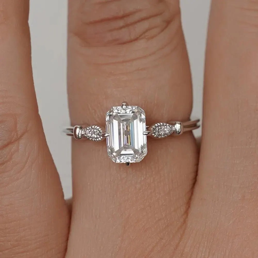 Elegant Emerald Cut Solitaire Engagement Ring In White Gold With Dainty Accent Stones. A Timeless Moissanite Wedding Or Promise Ring For Her